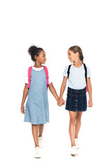 Obraz premium multicultural schoolgirls with backpacks holding hands and looking at each other isolated on white