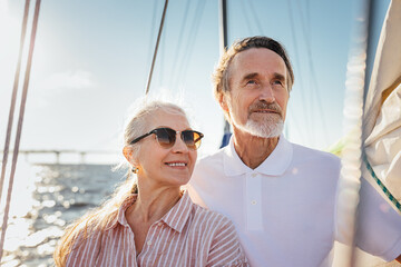 Portrait of two senior people looking away. Mature couple standing on yacht enjoying their sailing...