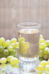 A glass of grape juice with grapes on the table, selective focus. Close-up.