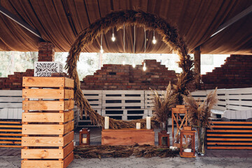 Wedding boho ceremony round arch decorated with reeds, lights, candles and wooden details. Rustic style © maryviolet