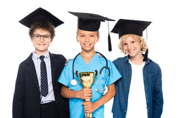 kids in graduation caps dressed in costumes of different professions holding trophy isolated on white