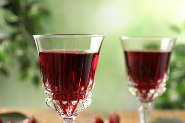 Delicious cherry wine on blurred green background, closeup