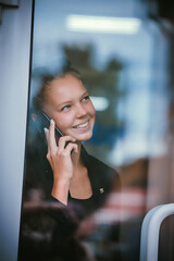 A teenage girl is standing outside the door happily talking on the phone