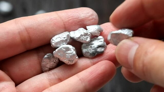 The hands of men are looking at the silver or platinum ore in their hands from the mine
