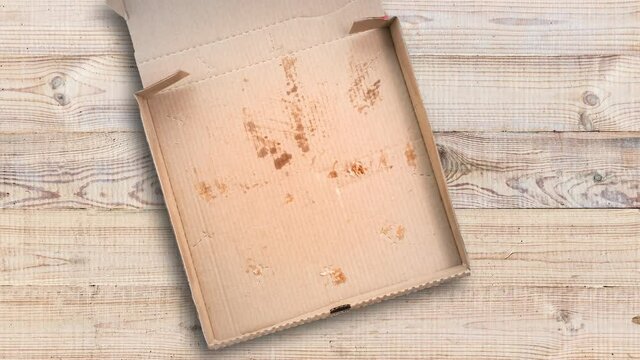 Stop motion animation with slices of pizza. empty cardboard box on the wooden table in restaurant. Top view and copy space for text
