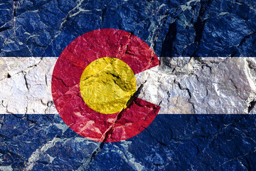 The national flag of the country of America, Colorado, in yellow, blue and white for Independence Day, grafted onto a textured stone rock wall. Political and religious disputes, customs and delivery.