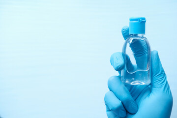 hand in protective gloves holding hand sanitizer 