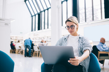 Female student using laptop in public library