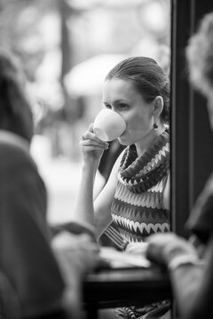 Woman sipping her coffee with friends at a street cafe