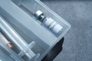 Close up of coronavirus vaccine and syringe on black background