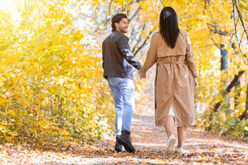 Excited man pulling his girlfriend while walking by forest