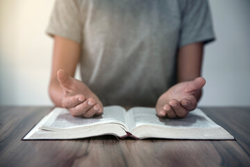 The hand of the girl praying with the palm Place on the Bible, the divine blessing of the church, the concept of Christian spirituality, worship and praise.
