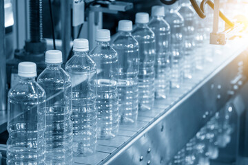The PET bottles  on the conveyor belt for filling process in the drinking water factory. The hi-technology of plastic bottle manufacturing process.