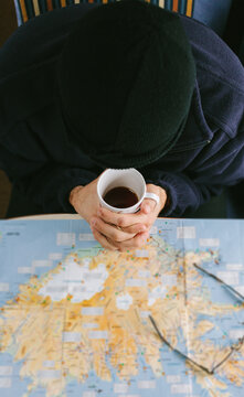 Man Checking a Map While Drinking a Coffee inside a Mobile Home
