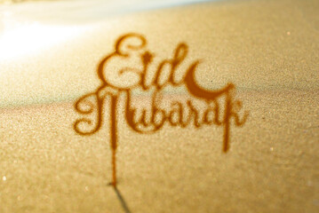 shadow text Eid Mubarak (in English Happy Holidays) on the sand