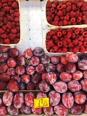 Ripe raspberries and plums on the market