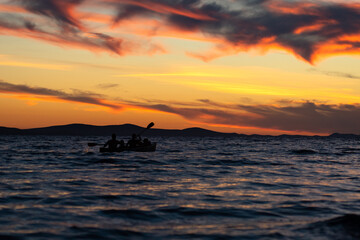 Fototapeta na wymiar ZADAR, CROATIA, summer 2020. Silhouette of people kayaking into the colorful sunset at the Adriatic sea