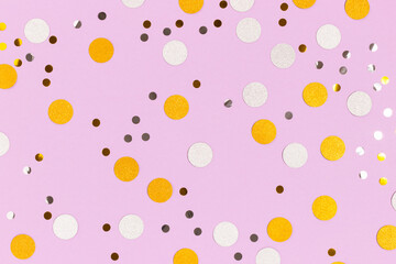 Golden and silver confetti scattered on a purple pastel background. Festive glowing backdrop.