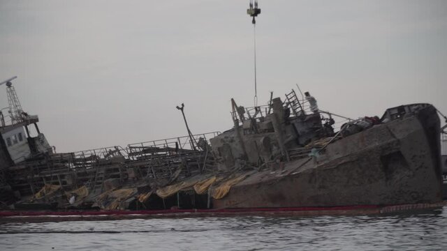 Oil tanker Delphi crashed near Black Sea coast in Ukraine, Odessa 26 August 2020. Small tanker, rusty old, lies on its side in sea. Lifting sunken ship with crane tug. Shipwreck disaster tanker Delfi