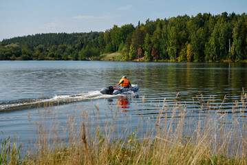 Power boat with people floating on the pond in the countryside in summer.