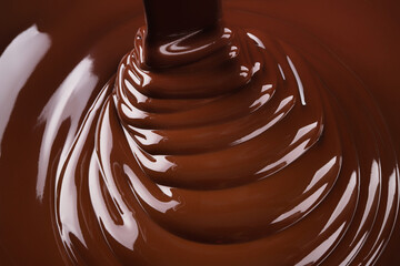 Ribbons hot chocolate pouring forming waves. stream of sweet syrup as background