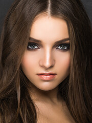 Fototapeta premium Young pretty female model with sophisticated makeup looking at camera isolated on black.