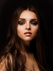 Fototapeta premium Young pretty female model with sophisticated makeup looking at camera isolated on black.