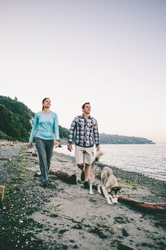 Couple walking with their dog on the beach