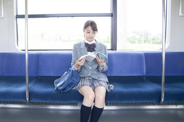 電車の中で勉強する女子高校生