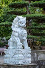 Marble white lion statue in outdoors park in tropical garden, Vietnam