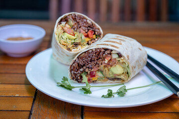 Vegan burrito. Sliced up raw food wrap with vegan ingredients on a plate