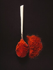 Silver teaspoon with hot red chilli pepper on a black background.