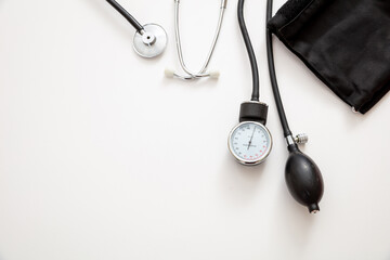 Medical stethoscope and sphygmomanometer on white background, top view.