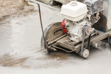 Worker using diamond saw blade machine cutting concrete road at construction site