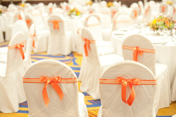 Wedding chairs decorated in white, and red ribbons with bows