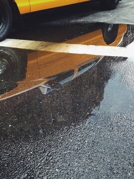 A yellow city taxi cab in reflection of a rainy street