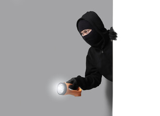 Burglar concept,Masked thief in balaclava with flashlight on gray background