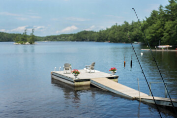Two fishing poles rest near a dock on a lake