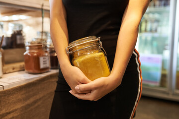 Zero waste food shopping. Hands with grocery products in reusable glass jars. Woman buying bulk dry goods in sustainable plastic free store. Eco-friendly low waste concept. Minimalist lifestyle