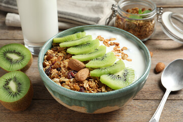 Tasty granola with yogurt and sliced kiwi for breakfast on wooden table