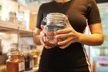 Zero waste food shopping. Hands with grocery products in reusable glass jars. Woman buying bulk dry goods in sustainable plastic free store. Eco-friendly low waste concept. Minimalist lifestyle