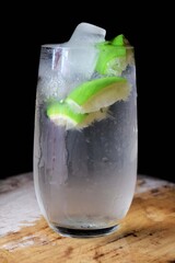 Glass of water with lemon and ice. Glass of Lemonade. Closeup view of a glass of lemon juice. Black background image. Mojito