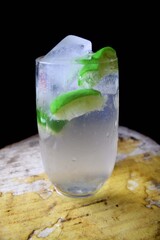Glass of water with lemon and ice. Glass of Lemonade. Closeup view of a glass of lemon juice. Black background image. Mojito
