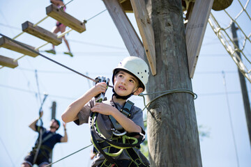 Boy with harness and helmet climbs on a ropes course