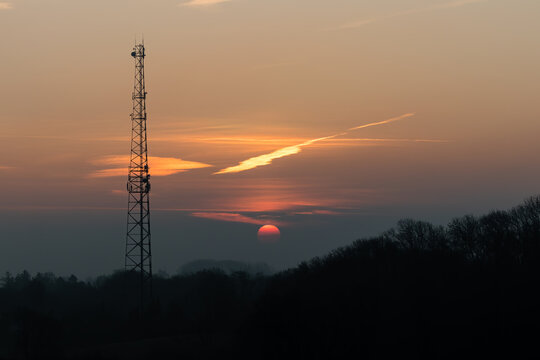 Masz z anteną telefoniczną na tle wschodzącego słońca, telekomunikacja, zasięg telefoniczny © PeterG