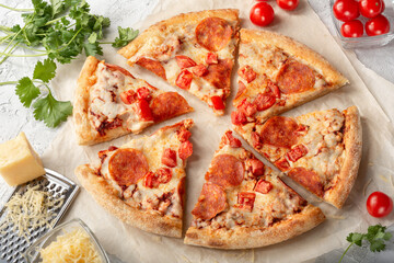 Pepperoni pizza on a light background. Pizza with sausage, tomato paste and tomatoes on a light background.