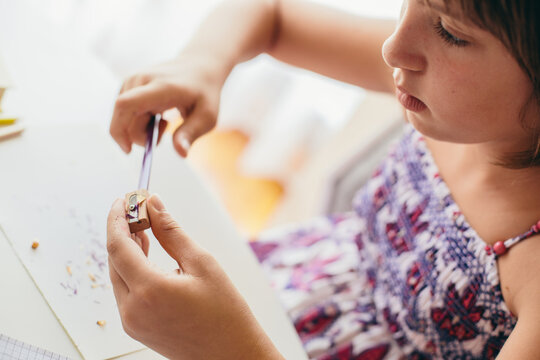 Young girl sharpening the pencil