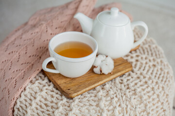 Obraz na płótnie Canvas A mug of hot tea, a teapot, a wooden stand on an ottoman. Cozy autumn. Winter breakfast. Cotton.