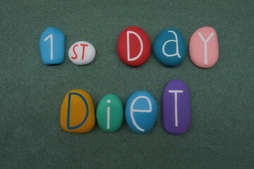 1st Day Diet, creative communication composed with multicolored stone letters over green sand