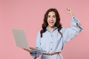 Happy young brunette woman 20s wearing casual blue shirt dress posing working on laptop pc computer...